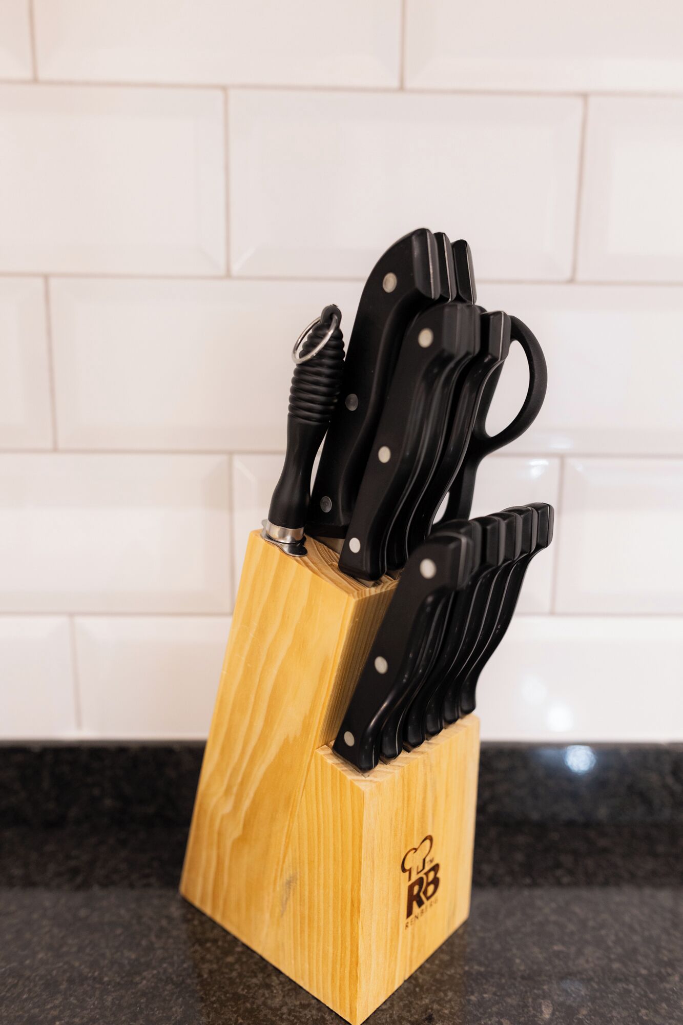 A wooden knife block with several knives on a kitchen counter.