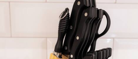 A wooden knife block with several knives on a kitchen counter.