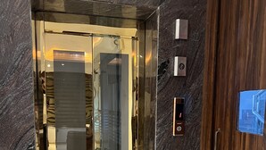 Ein moderner Aufzug mit Glastür und Holzverkleidung.