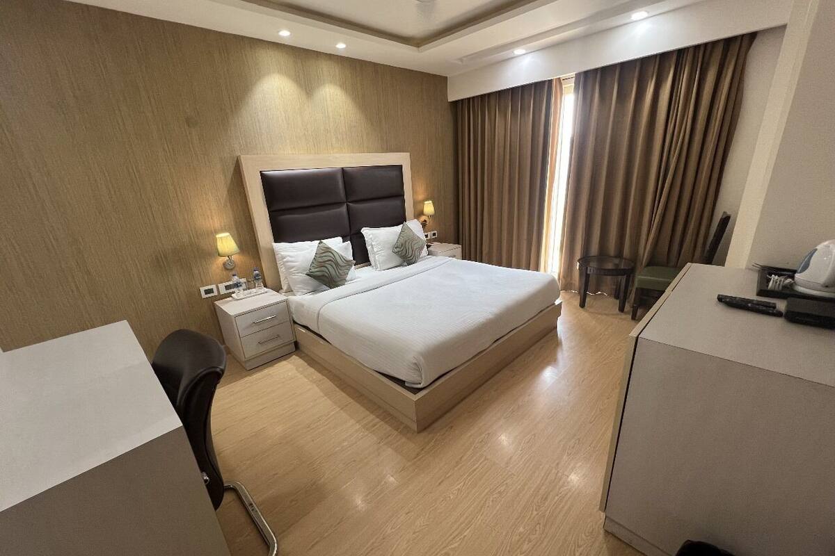 Una habitación de hotel moderna con una cama grande, mesitas de noche, un escritorio y una silla.