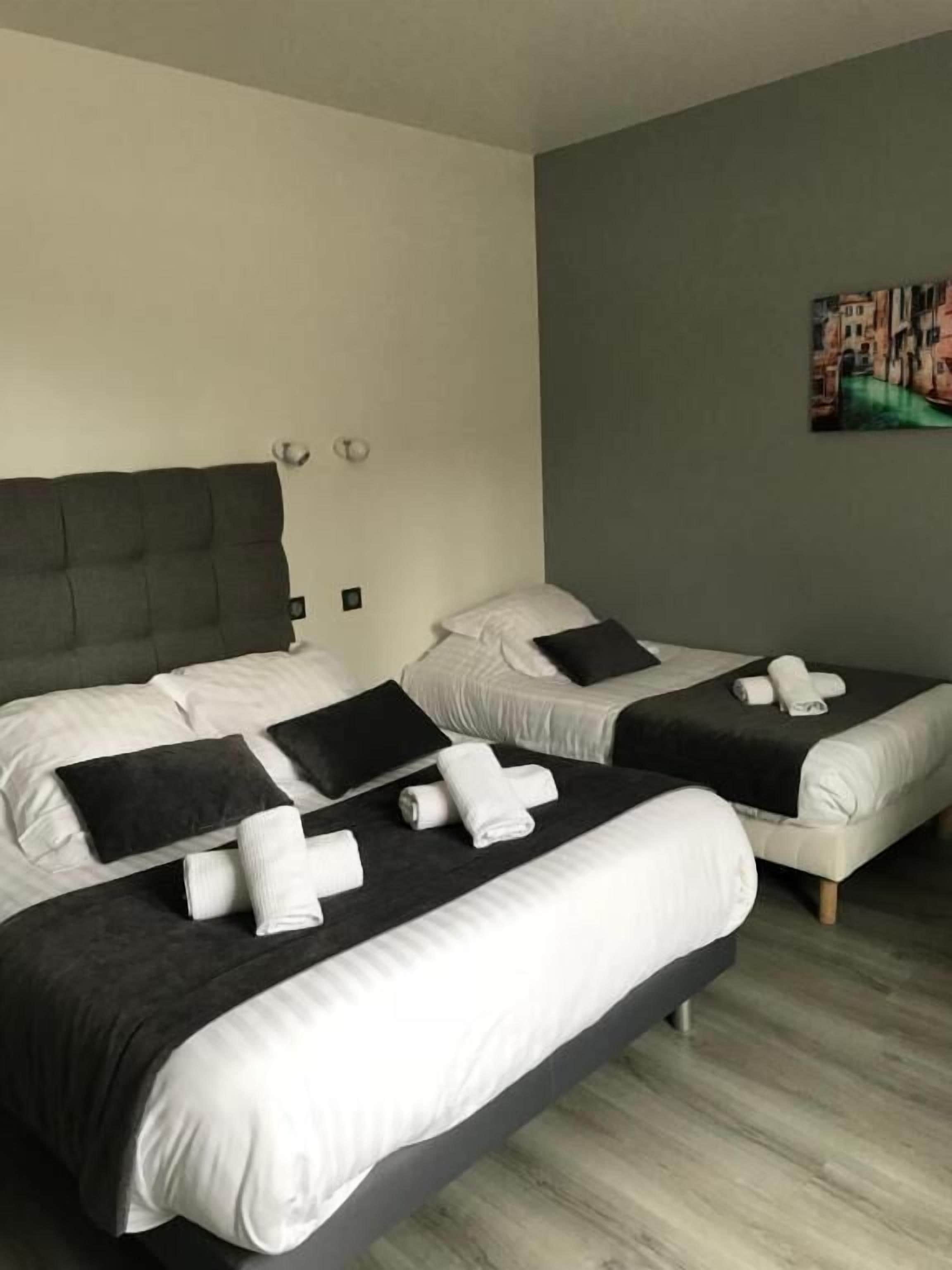 A hotel room with two beds, each with black and white bedding, and a painting on the wall.