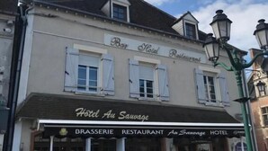 Un edificio con un letrero que dice "Hotel Au Sauvage" y "RESTAURANTE BRASSERIE".