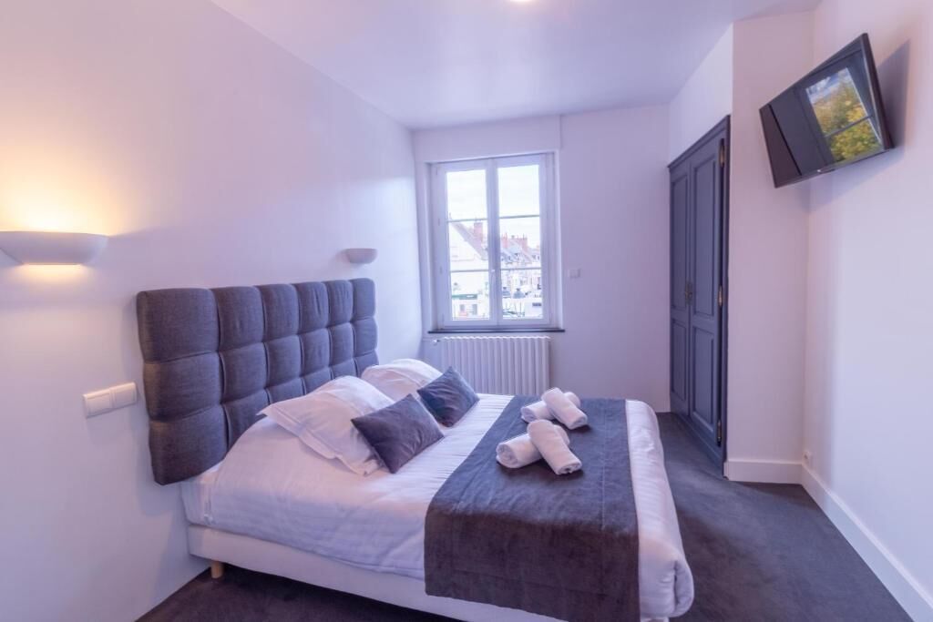 Een moderne slaapkamer met een groot bed, een raam, een flatscreen-tv en een radiator.