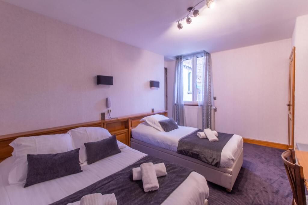 Habitación de hotel con dos camas, un espejo, un televisor y una ventana con cortinas.