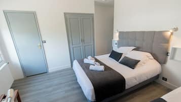 A modern hotel room with a large bed, a wardrobe, and a bedside lamp.