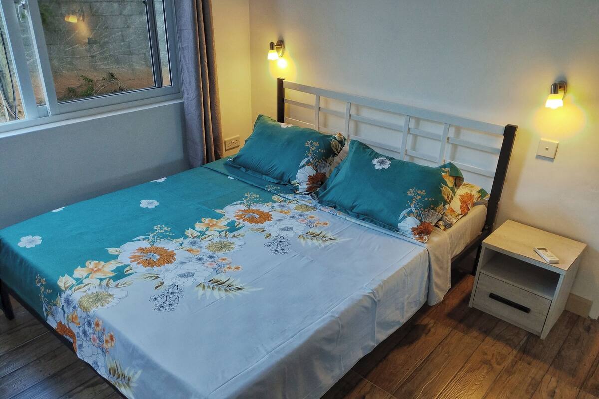 Ein Bett mit floraler Bettwäsche, zwei Nachttische und Wandleuchten.