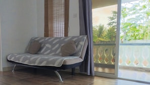 Une chambre moderne avec un canapé, une grande fenêtre et un balcon agrémenté de plantes.
