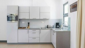 Una cucina moderna con mobili bianchi, forno integrato, tostapane e scolapiatti.