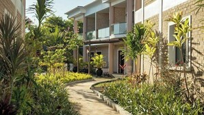 Un edificio a più piani con una zona esterna coperta, immerso nel verde e con un vialetto curvo.