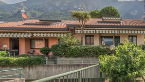 A building with a tiled roof, a balcony, and a view of mountains. - Casa Mimosa in Lierna (Lierna)