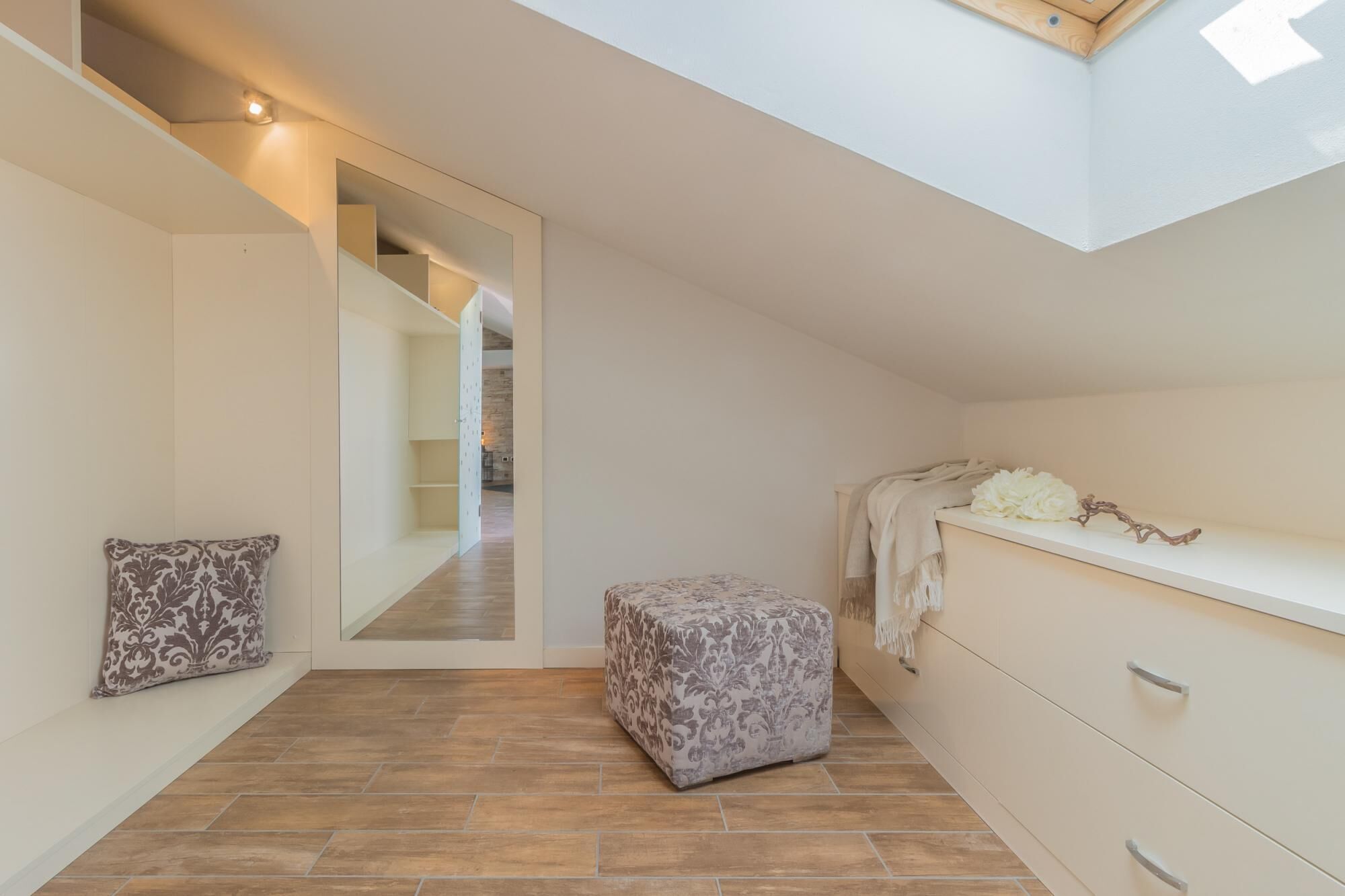 A modern, minimalist room with a built-in bench, a bench with a floral pattern, and a bench with a white and gray pattern.