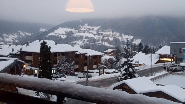 Un pueblo montañoso cubierto de nieve, con edificios y una carretera.