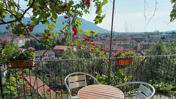 A balcony with metal chairs and a wooden table, surrounded by potted plants and flowers. - Historic home in the heart of the medieval village of Avigliana (Avigliana)