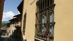A narrow street with buildings featuring barred windows and potted plants. - Historic home in the heart of the medieval village of Avigliana (Avigliana)