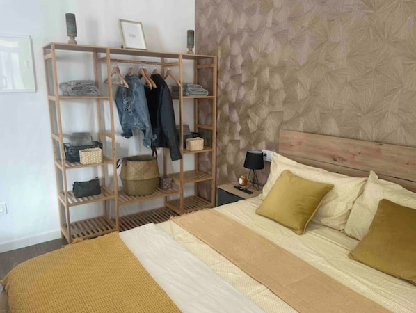 Une chambre à coucher avec un lit, une armoire en bois, une table de chevet et un mur décoré d’un motif.