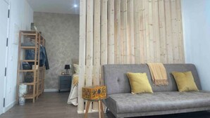 Una sala moderna con un sofá gris, un panel de pared de madera y una mesita con una caja decorativa.