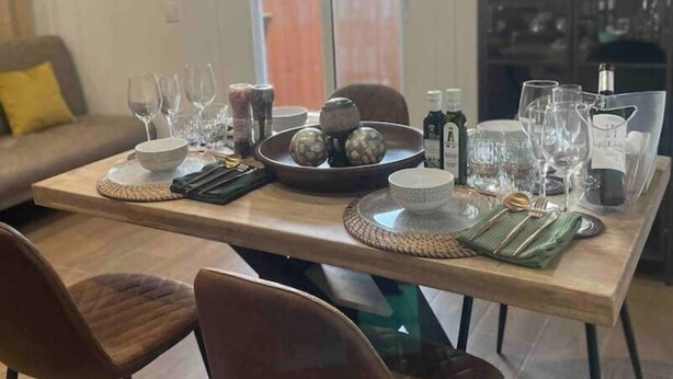 Un comedor con una mesa de madera dispuesta para cuatro personas, rodeado de sillas.