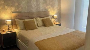 Un dormitorio con una cama grande, dos mesitas de noche con lámparas y una ventana con cortinas.