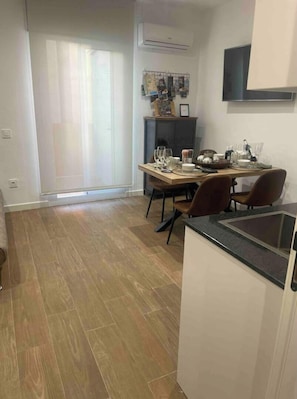 Une cuisine moderne avec un coin repas, un plancher en bois et une grande fenêtre avec des rideaux.