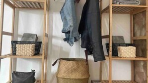 Un armario de madera con varios estantes, algunos con ropa doblada y otros con cestas.
