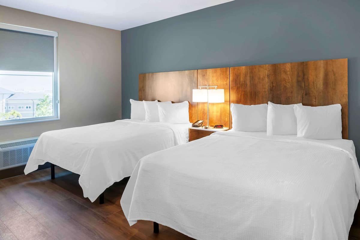 Een hotelkamer met twee bedden, een nachtkastje, een lamp en een raam met uitzicht.