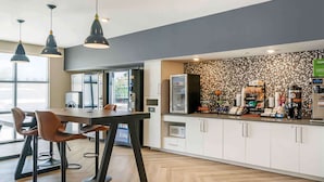 Een moderne keuken met een bar, zitplaatsen en een koffiehoek.