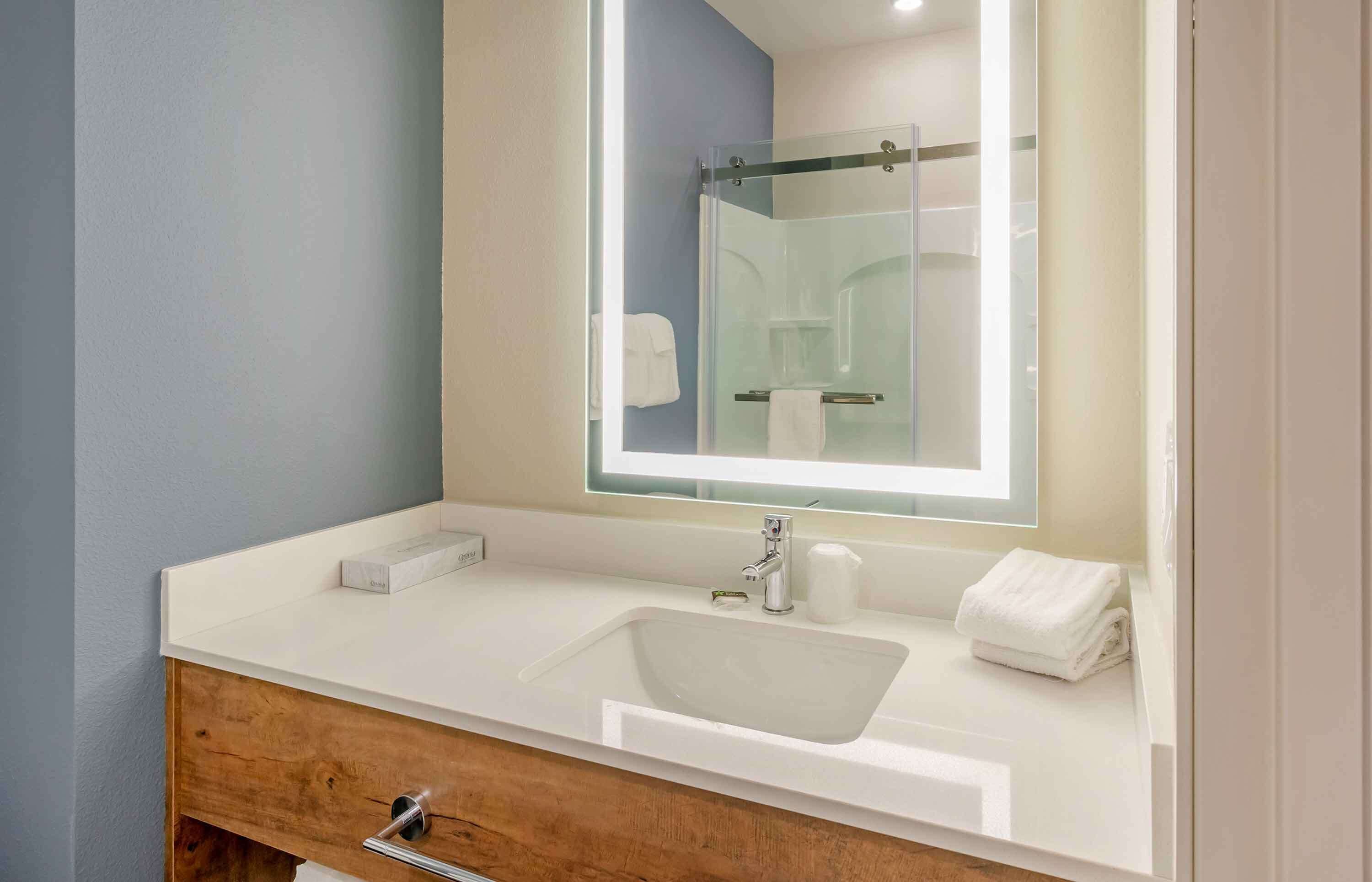A bathroom with a white sink, a mirror, and a glass shower enclosure.