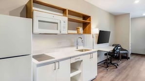 Een moderne keuken met een magnetron, spoelbak en houten planken.