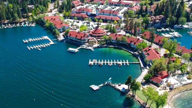 Vista aérea de un complejo turístico a orillas de un lago, con varias edificaciones, muelles y embarcaciones.