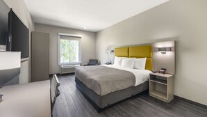 Una habitación de hotel moderna con una cama grande, una mesita de noche y un escritorio con una silla.