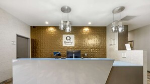 Un mostrador de recepción de hotel con diseño moderno, que cuenta con una barra grande, una computadora y un cartel que dice 
