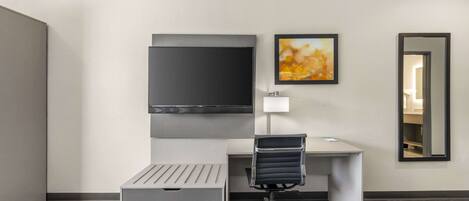 Una habitación de hotel moderna con escritorio, silla y un televisor de pantalla plana grande montado en la pared.