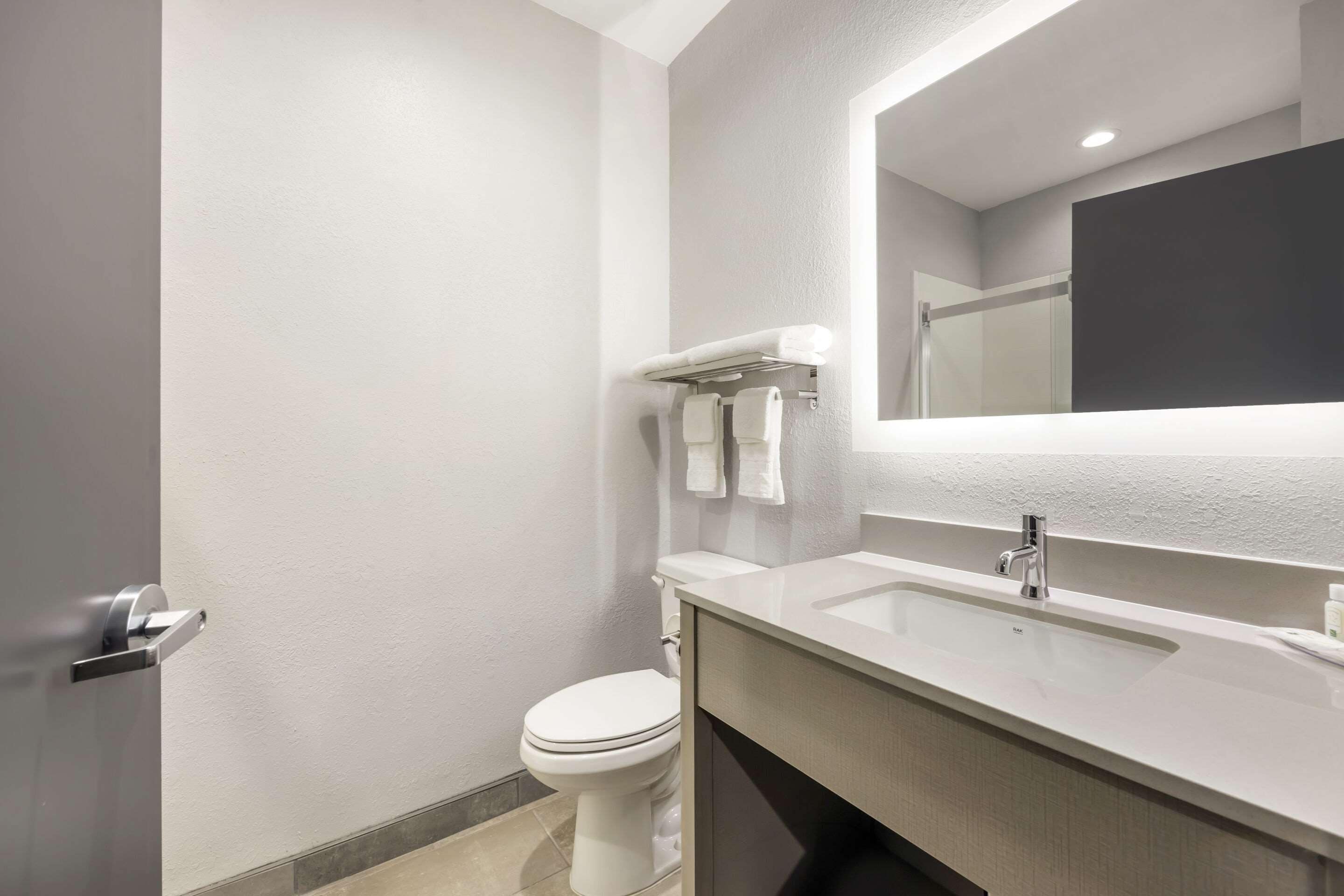 Une salle de bain moderne équipée de toilettes, d’un lavabo et d’un miroir.