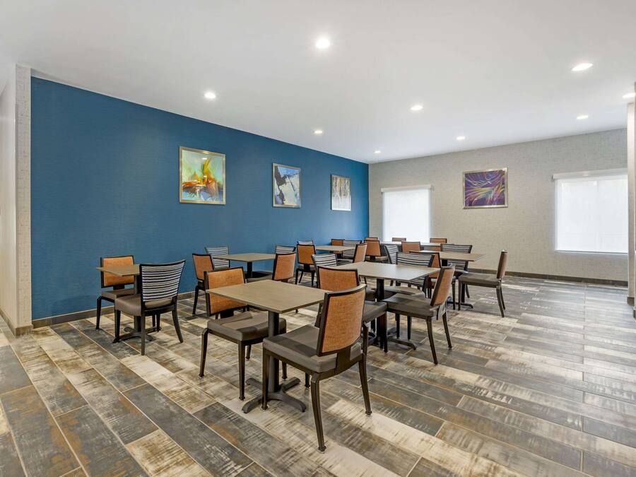 Un salón de conferencias con una pared azul de acento, suelo de madera y varias mesas y sillas.