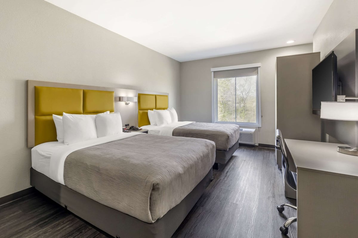 Una habitación de hotel con dos camas, un escritorio, un televisor y una ventana.