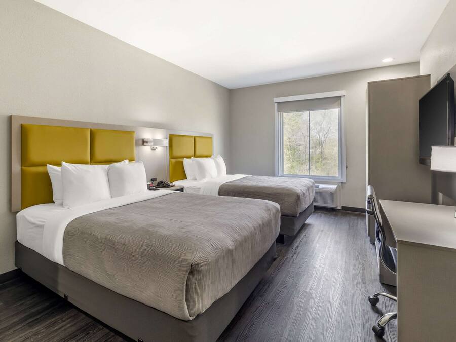Une chambre d’hôtel avec deux lits, un bureau, une télévision et une fenêtre.