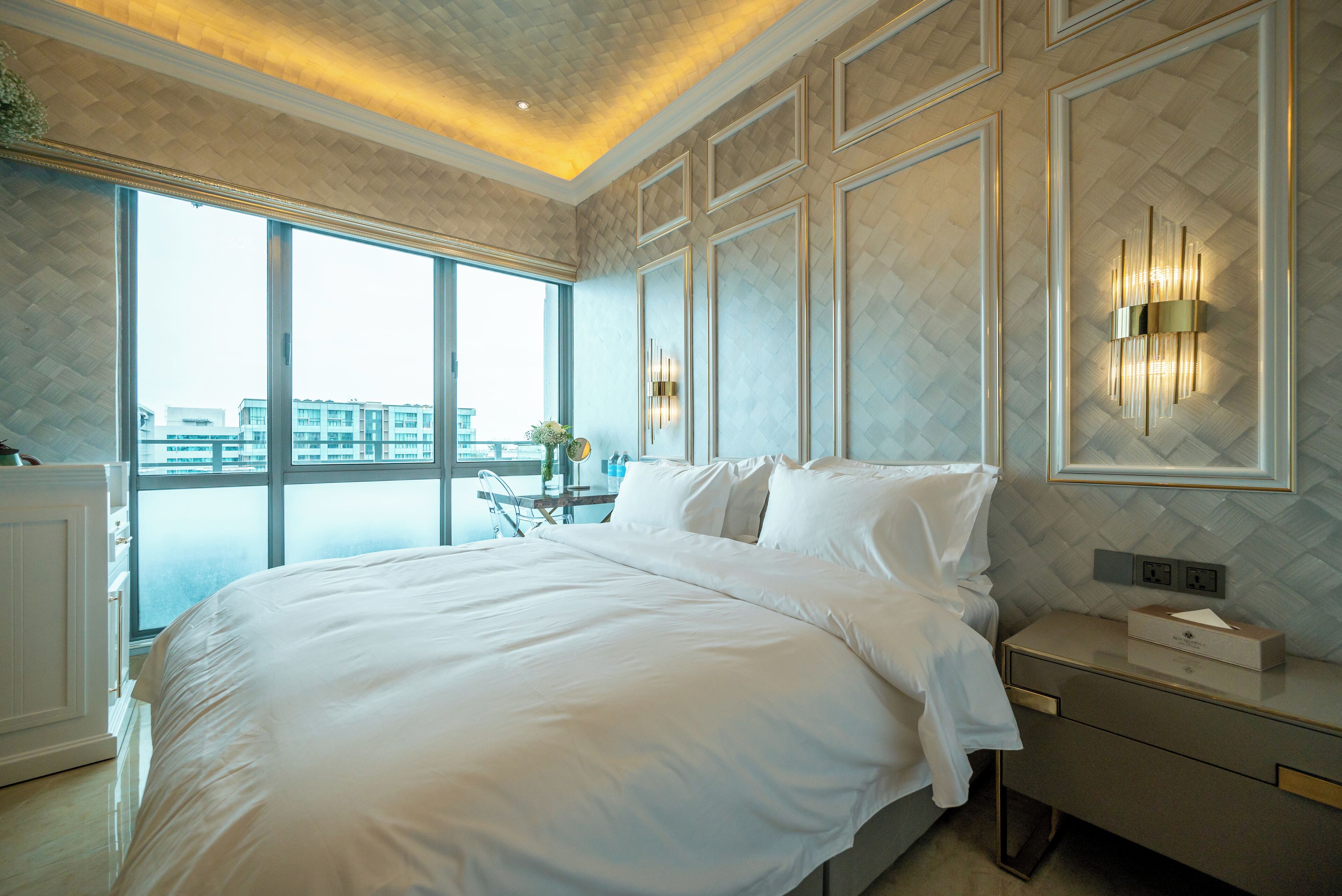 Ein modernes Hotelzimmer mit einem großen Bett, einem Nachttisch und einer Wandleuchte.