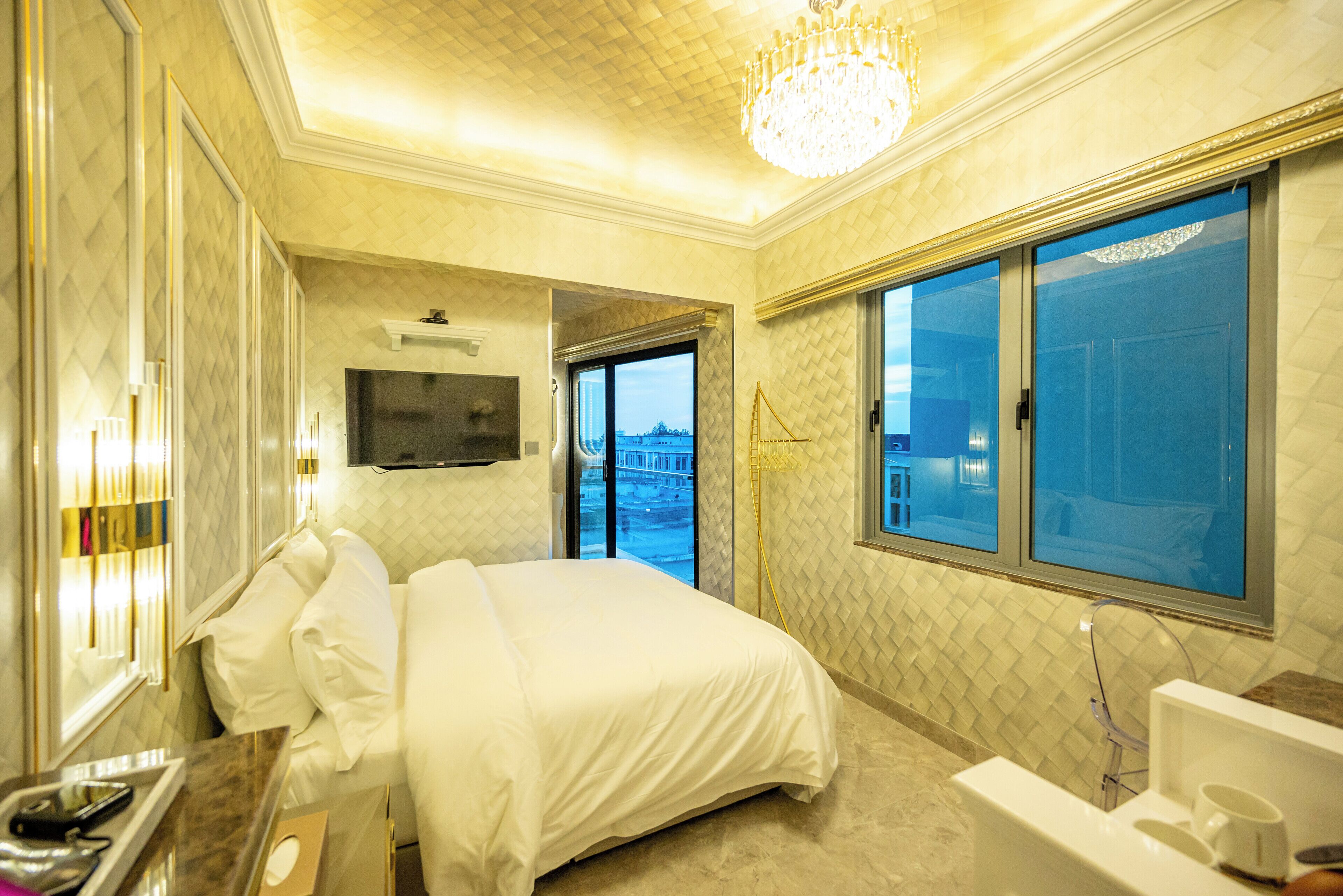 Habitación de hotel con una cama grande, televisión, baño con bañera y vista a la ciudad desde la ventana.