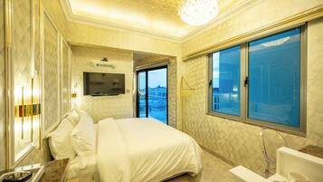 Habitación de hotel con una cama grande, televisión, baño con bañera y vista a la ciudad desde la ventana.