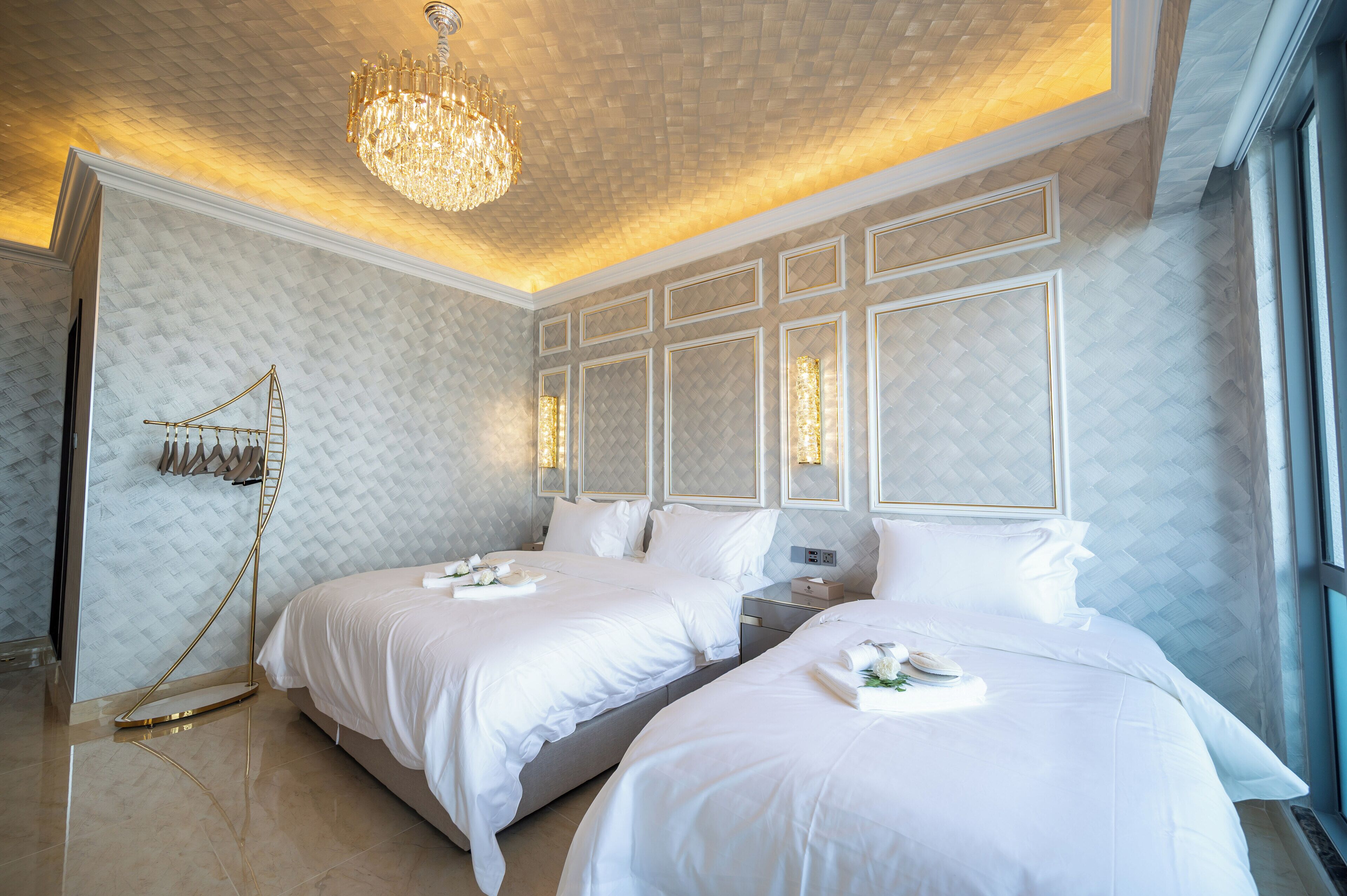 Una habitación de hotel con dos camas, un candelabro y un ventanal grande.