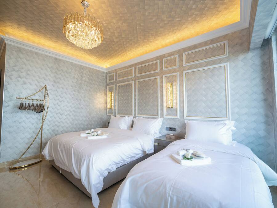 Una habitación de hotel con dos camas, un candelabro y un ventanal grande.