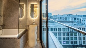 A modern bathroom with a large bathtub, a unique sink, and a large window offering a city view. - Ritz Residence - A Member of The Luxury Hotel Group (Kota Kinabalu)