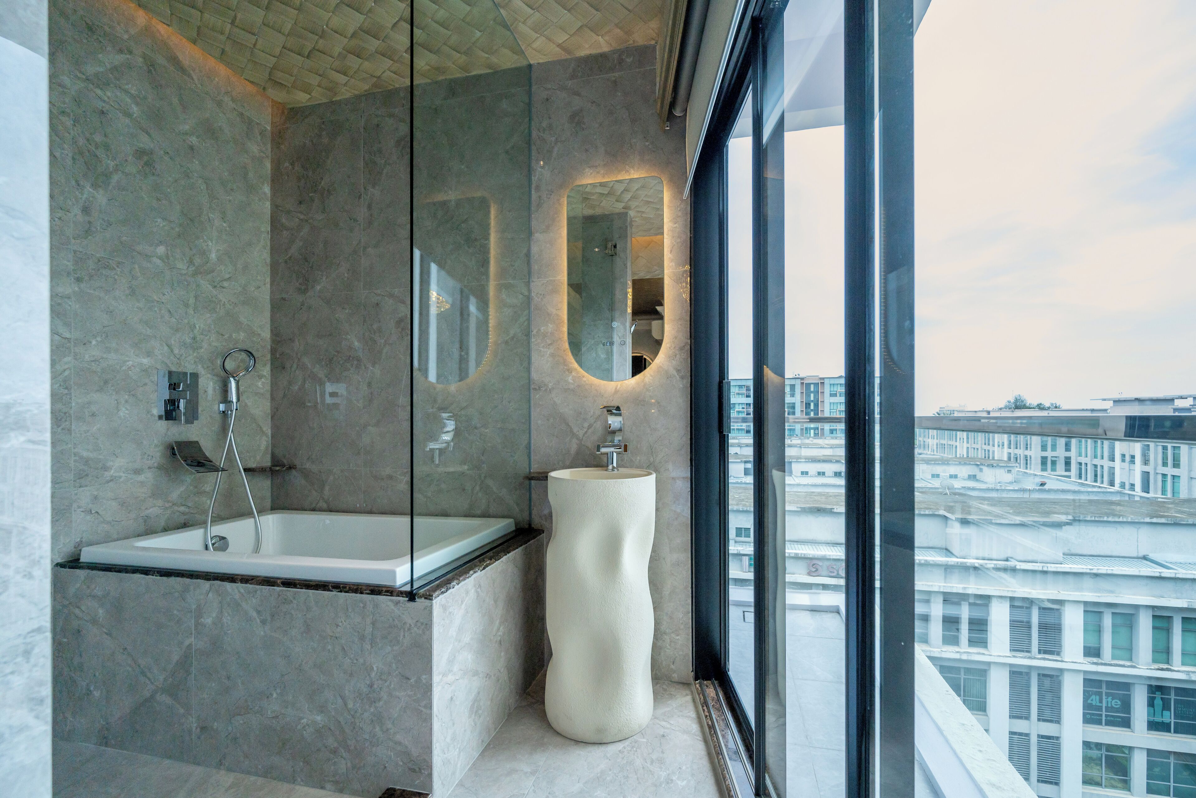 Un baño moderno con ducha de vidrio, lavamanos de mármol y un espejo grande.