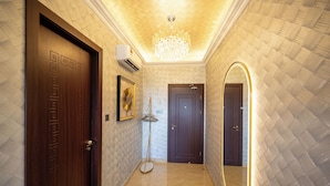 A hallway with a wooden door, a mirror, and a chandelier. - Ritz Residence - A Member of The Luxury Hotel Group (Kota Kinabalu)