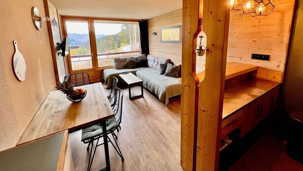 Una cabaña acogedora con comedor, sofá y cocina.