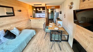 Un espacio habitable compacto con kitchenette, comedor y televisor.