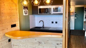 Una cocina compacta con encimera de madera, un lavabo y un microondas.