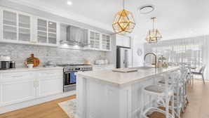 A modern kitchen with white cabinetry, a central island, and pendant lighting.