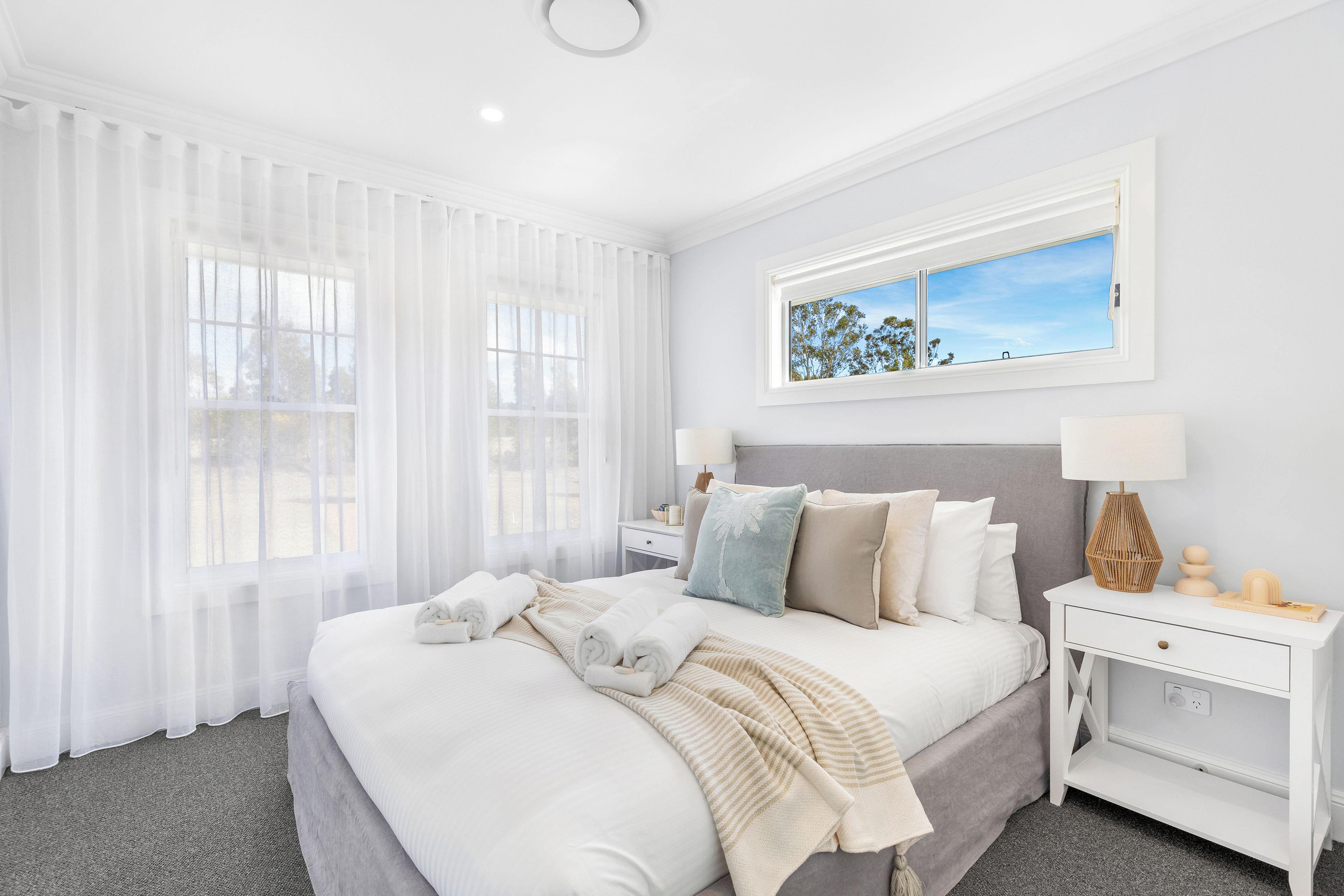 A hotel room with a large bed, a nightstand, a lamp, and a window with a view of trees.