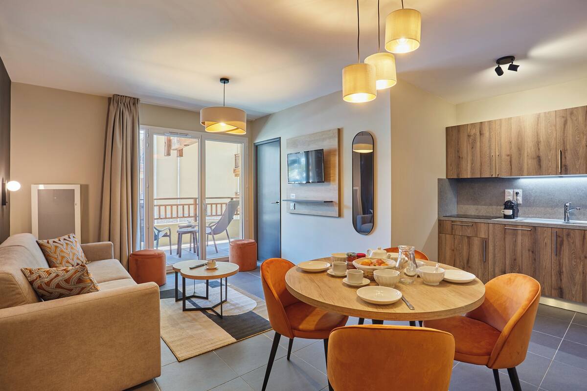 A modern living room with a sofa, coffee table, and dining area with chairs and a table set for breakfast.